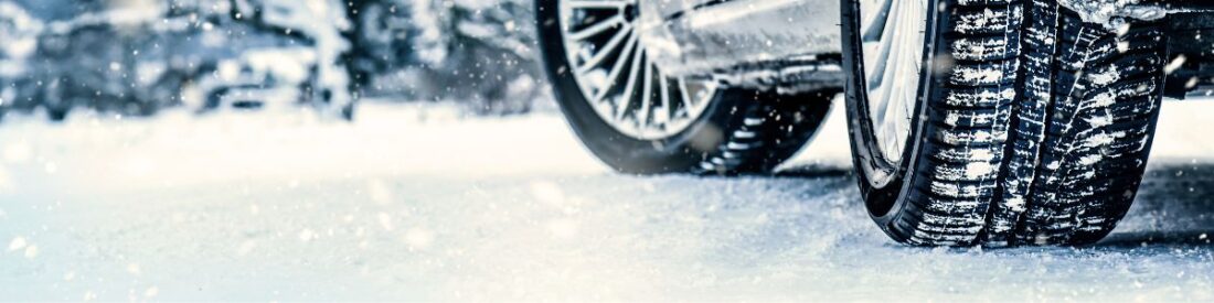 Close-up of snow-covered tires on a vehicle, illustrating the importance of prepping your car for winter driving conditions.